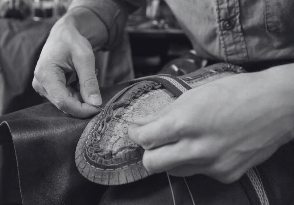 Uomo che produce scarpe in pelle vera, cucendo a mano il bordo della scarpa attorno alla forma del piede. Scarpe italiane di lusso, realizzate con pelle di alta qualità e design artigianale.