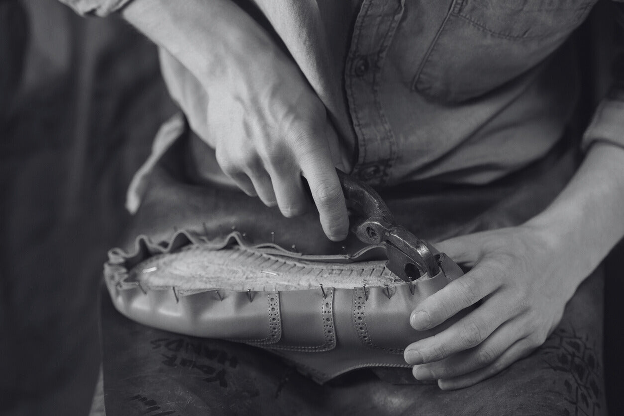 Artigiano al lavoro su una scarpa in pelle, simbolo della tradizione e dell'eccellenza artigianale delle scarpe italiane firmate Poiché Milano.